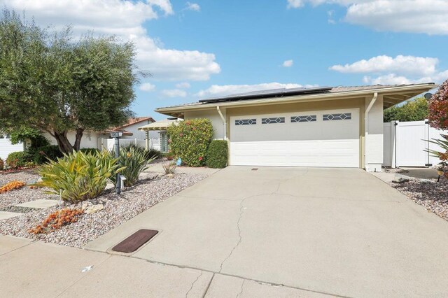 16407 Gabarda Rd, San Diego, CA 92128 - view of front of home featuring roof mounted solar panels, driveway, a gate, a garage, and stucco siding