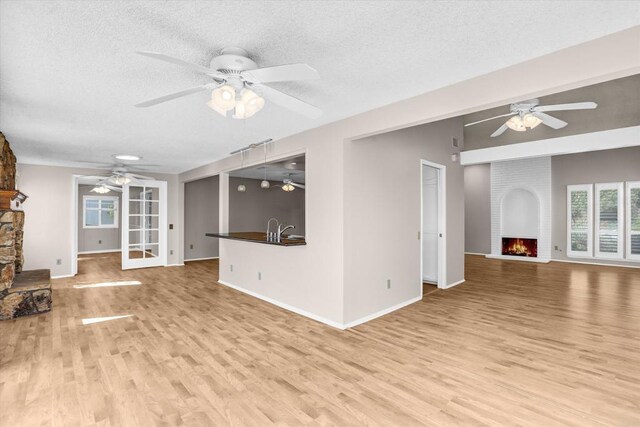 16407 Gabarda Rd, San Diego, CA 92128 - unfurnished living room with a fireplace, ceiling fan, light wood finished floors, and a textured ceiling