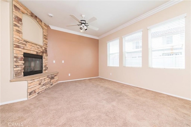 unfurnished living room with baseboards, a ceiling fan, crown molding, a stone fireplace, and carpet floors