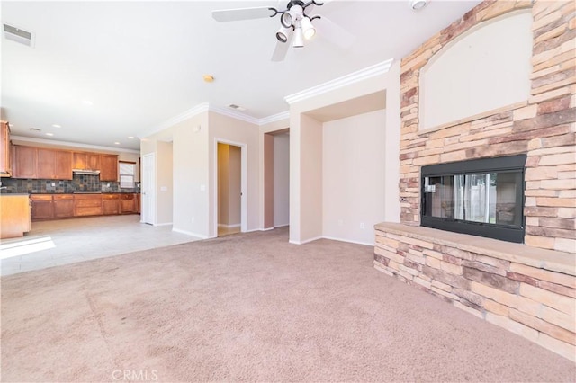 unfurnished living room with visible vents, light carpet, crown molding, baseboards, and a fireplace