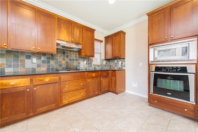 kitchen featuring backsplash, brown cabinets, crown molding, under cabinet range hood, and appliances with stainless steel finishes