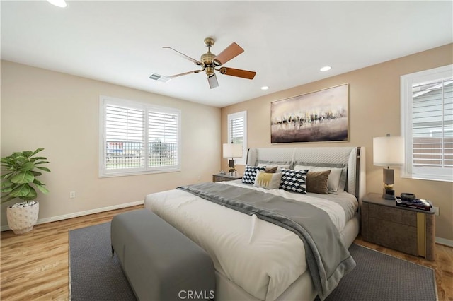 bedroom with baseboards, recessed lighting, wood finished floors, and visible vents