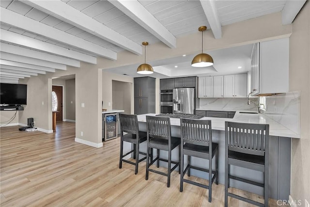 kitchen featuring baseboards, light countertops, wine cooler, stainless steel appliances, and light wood finished floors