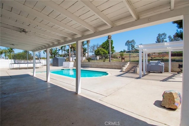 view of swimming pool featuring a shed, a patio, a fenced backyard, and an outbuilding