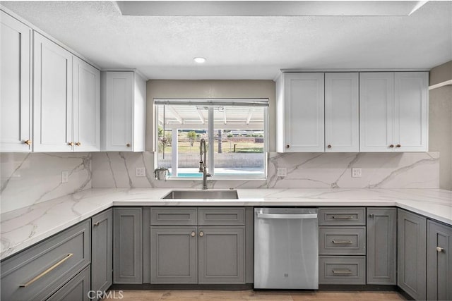kitchen featuring a sink, gray cabinetry, dishwasher, and a textured ceiling