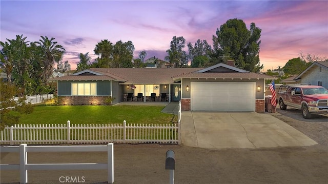 single story home with a front yard, a garage, concrete driveway, brick siding, and fence private yard