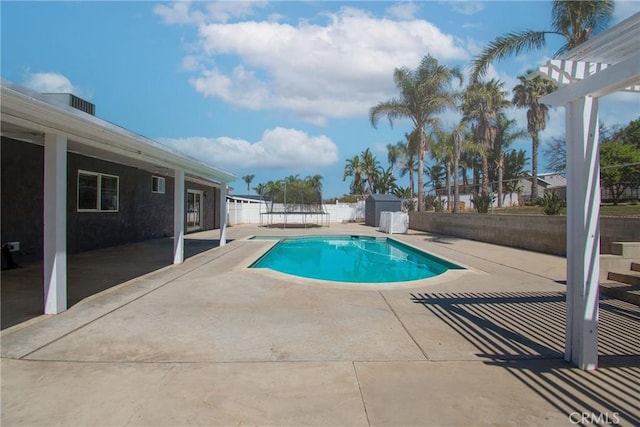pool featuring a patio area, an outdoor structure, a fenced backyard, and a storage shed