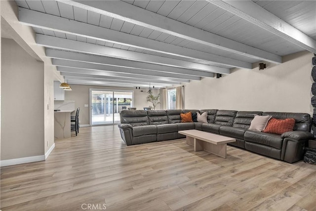 living area featuring baseboards, beamed ceiling, and wood finished floors
