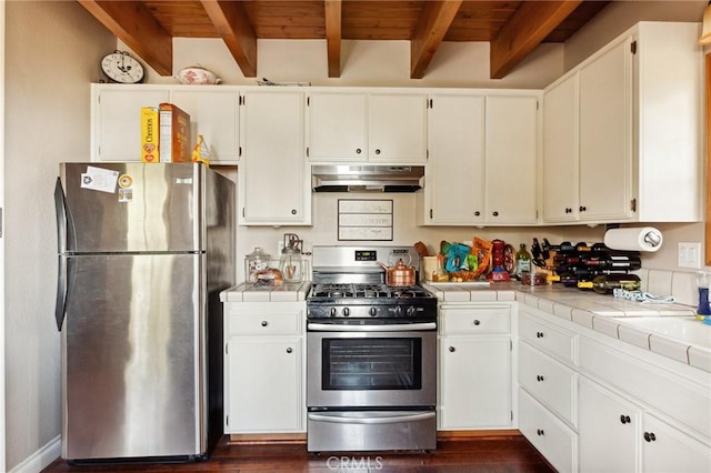 kitchen featuring tile countertops, wood ceiling, appliances with stainless steel finishes, under cabinet range hood, and beam ceiling