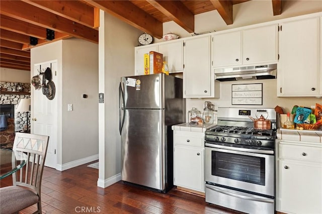 kitchen featuring under cabinet range hood, dark wood-type flooring, beam ceiling, appliances with stainless steel finishes, and tile countertops