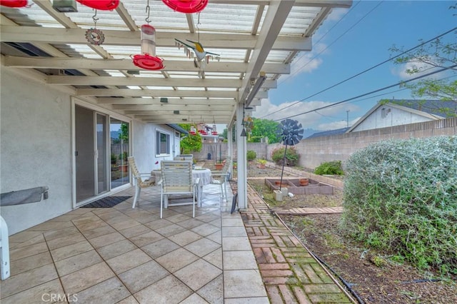 view of patio featuring a pergola, outdoor dining area, fence, and a vegetable garden