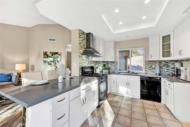 kitchen featuring wall chimney range hood, dark countertops, a sink, black appliances, and visible vents