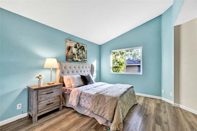 bedroom featuring wood finished floors, lofted ceiling, and baseboards