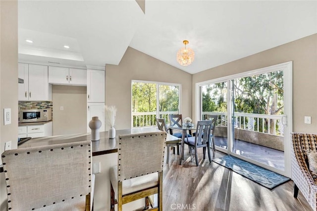 dining room featuring a tray ceiling, vaulted ceiling, an inviting chandelier, recessed lighting, and wood finished floors