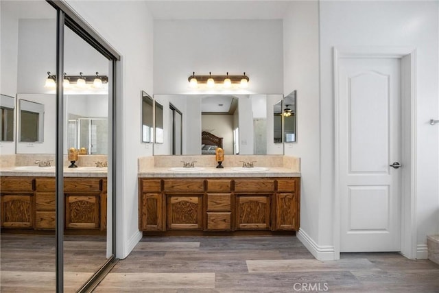 full bath featuring a sink, double vanity, and wood finished floors