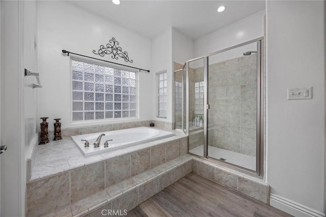 bathroom with recessed lighting, a stall shower, wood finished floors, and a garden tub