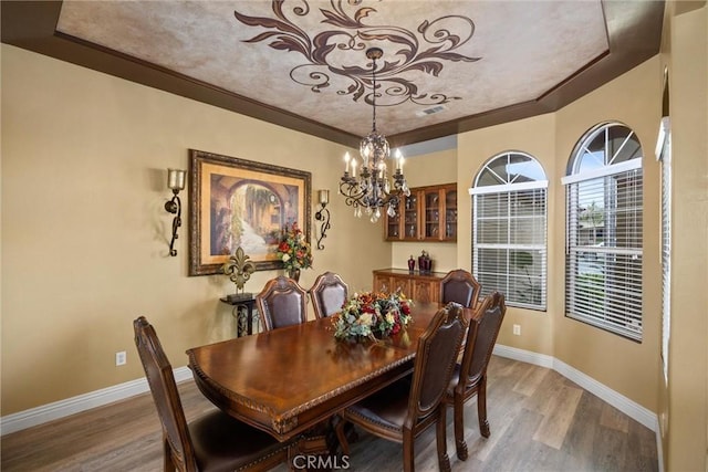 dining area with a chandelier, light wood-style floors, and baseboards