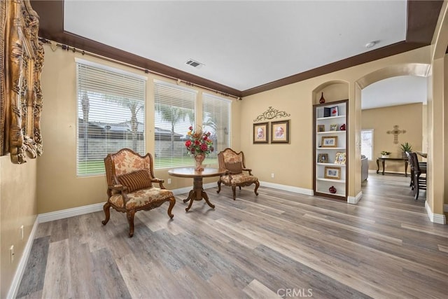 living area featuring arched walkways, wood finished floors, visible vents, and a wealth of natural light