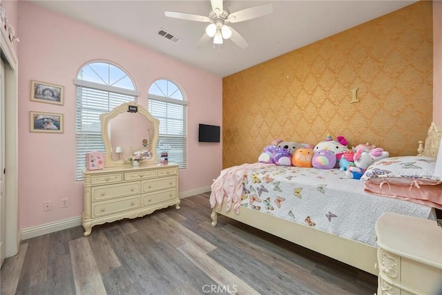bedroom featuring wallpapered walls, an accent wall, baseboards, and visible vents