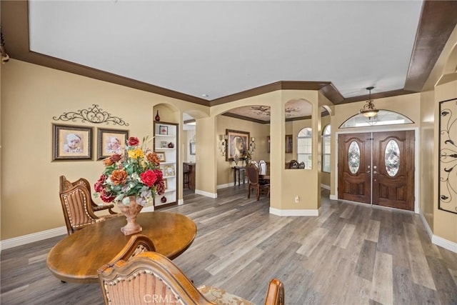 entryway with ornamental molding, baseboards, arched walkways, and wood finished floors