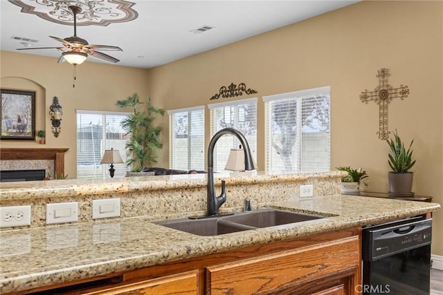 kitchen with light stone countertops, a ceiling fan, visible vents, dishwasher, and a sink