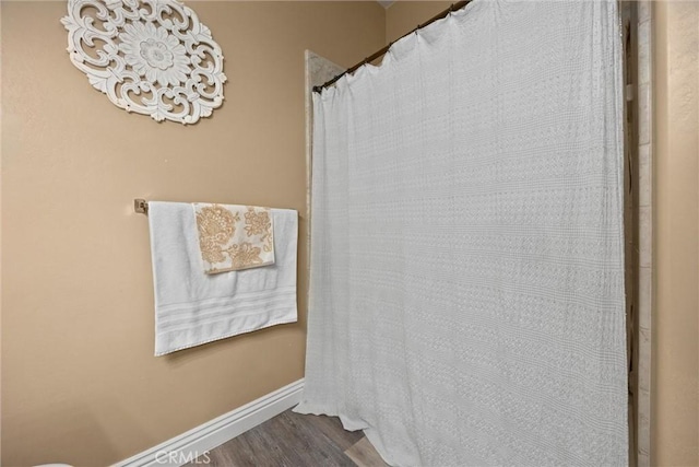 full bath featuring baseboards, curtained shower, and wood finished floors