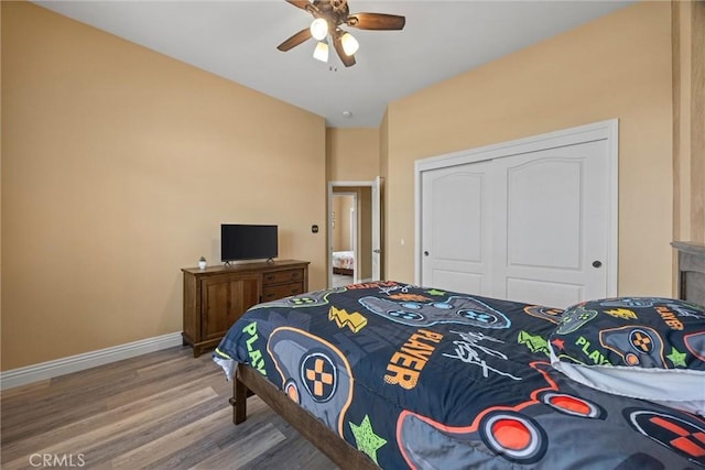 bedroom featuring a closet, baseboards, ceiling fan, and wood finished floors