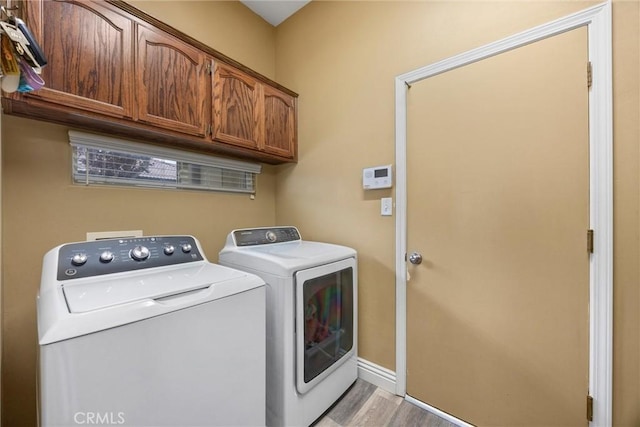 clothes washing area featuring cabinet space, light wood-style flooring, washing machine and dryer, and baseboards