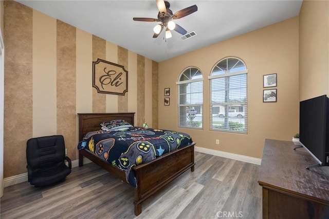 bedroom with wood finished floors, baseboards, a ceiling fan, and visible vents