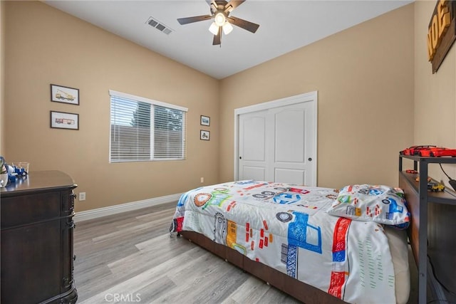 bedroom featuring ceiling fan, a closet, visible vents, light wood finished floors, and baseboards