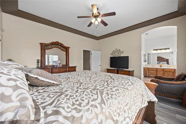bedroom with crown molding, a ceiling fan, connected bathroom, arched walkways, and wood finished floors