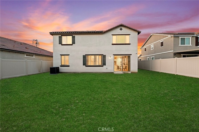 29553 Tulipwood St, Menifee, CA 92584 - back of property at dusk with a tiled roof, central air condition unit, a fenced backyard, stucco siding, and a lawn
