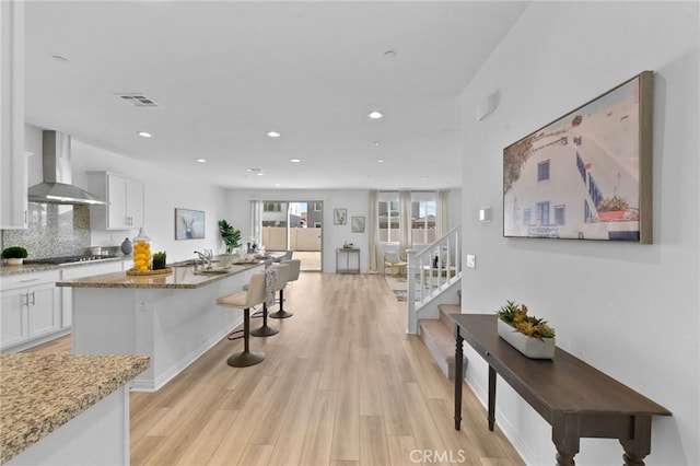 29553 Tulipwood St, Menifee, CA 92584 - kitchen featuring visible vents, light wood-style flooring, white cabinetry, and wall chimney exhaust hood