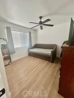 living area featuring baseboards, a ceiling fan, and wood finished floors