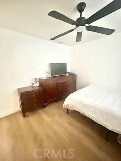 bedroom with light wood-style floors, a ceiling fan, and baseboards