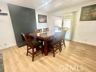 dining space featuring light wood-type flooring and baseboards