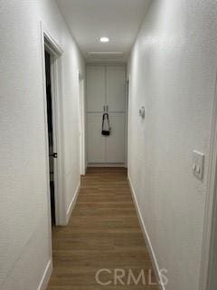 corridor with wood finished floors and baseboards