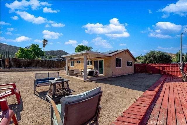 rear view of house featuring a mountain view, a fenced backyard, stucco siding, and solar panels