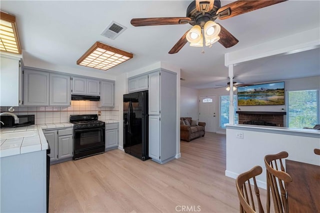 kitchen with gray cabinets, visible vents, black appliances, and tile counters
