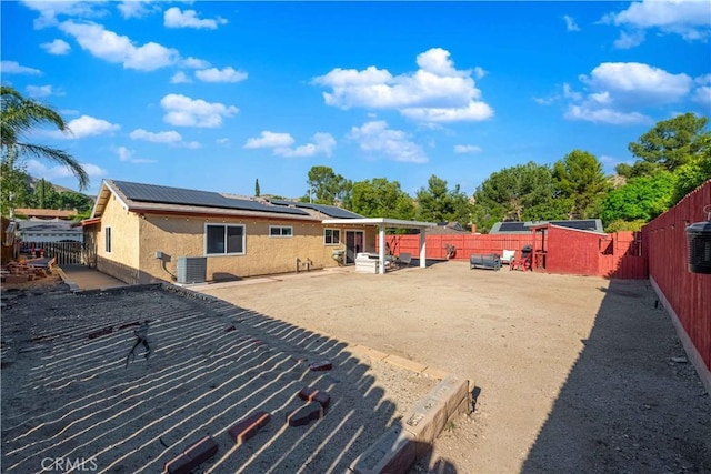 rear view of property with a patio, a fenced backyard, and solar panels