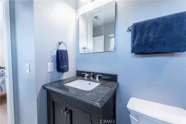 half bathroom featuring toilet, vanity, and visible vents