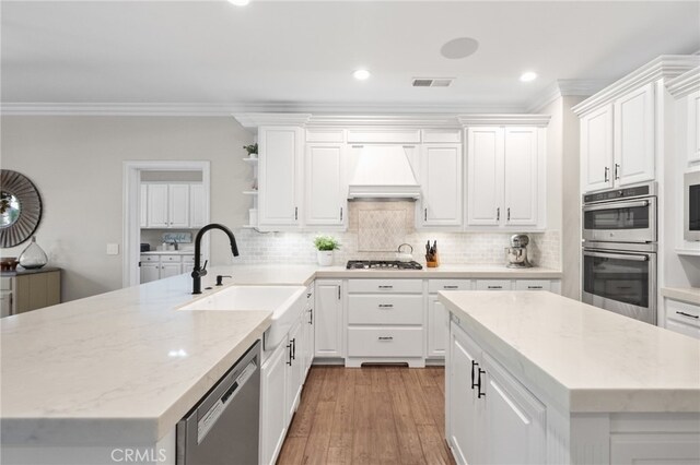 kitchen featuring crown molding, visible vents, a sink, and premium range hood