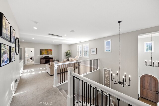 corridor with carpet floors, a chandelier, recessed lighting, baseboards, and an upstairs landing
