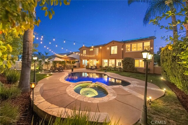 pool at twilight featuring a patio, an in ground hot tub, and an outdoor pool