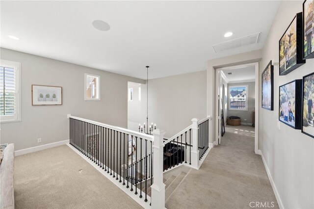 corridor featuring visible vents, baseboards, an upstairs landing, and carpet
