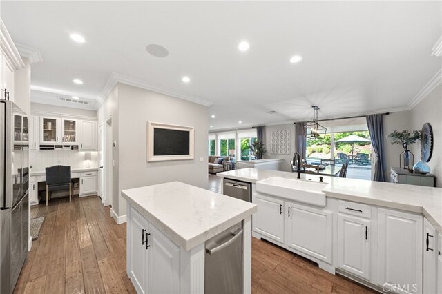kitchen featuring crown molding, high end fridge, a sink, white cabinetry, and recessed lighting