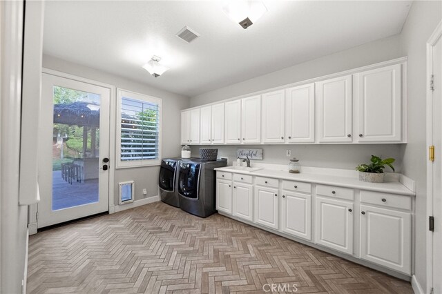 clothes washing area featuring cabinet space, washer and dryer, a sink, baseboards, and visible vents
