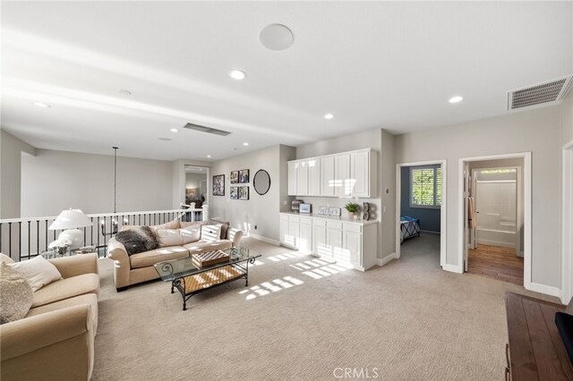 living room featuring baseboards, light colored carpet, recessed lighting, and visible vents