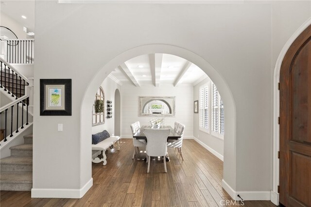 dining area with wood-type flooring, arched walkways, baseboards, and stairs