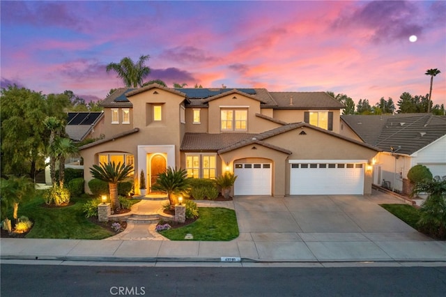 view of front of house with stucco siding, roof mounted solar panels, a tiled roof, an attached garage, and driveway